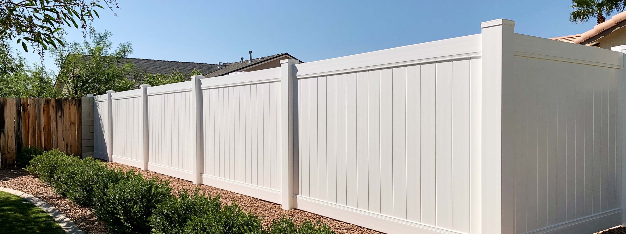 A white vinyl fence along the back of a Queen Creek yard in full sun